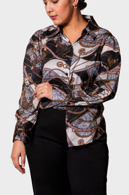 A woman wearing a long-sleeve button-up shirt with an abstract chain and rope pattern in black, white, and brown, paired with black pants, against a light gray background.